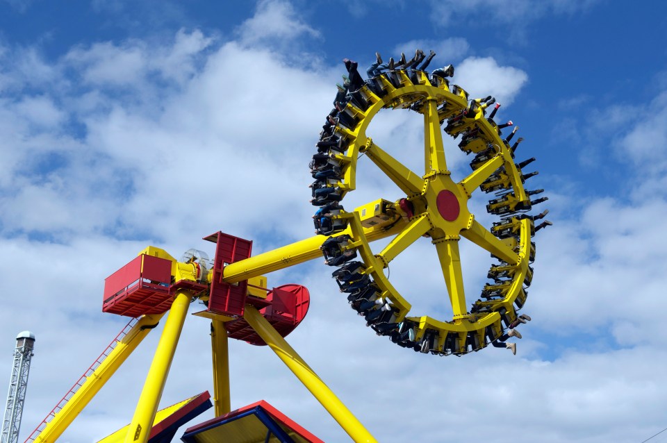 A yellow and red amusement park ride with people spinning in the air.