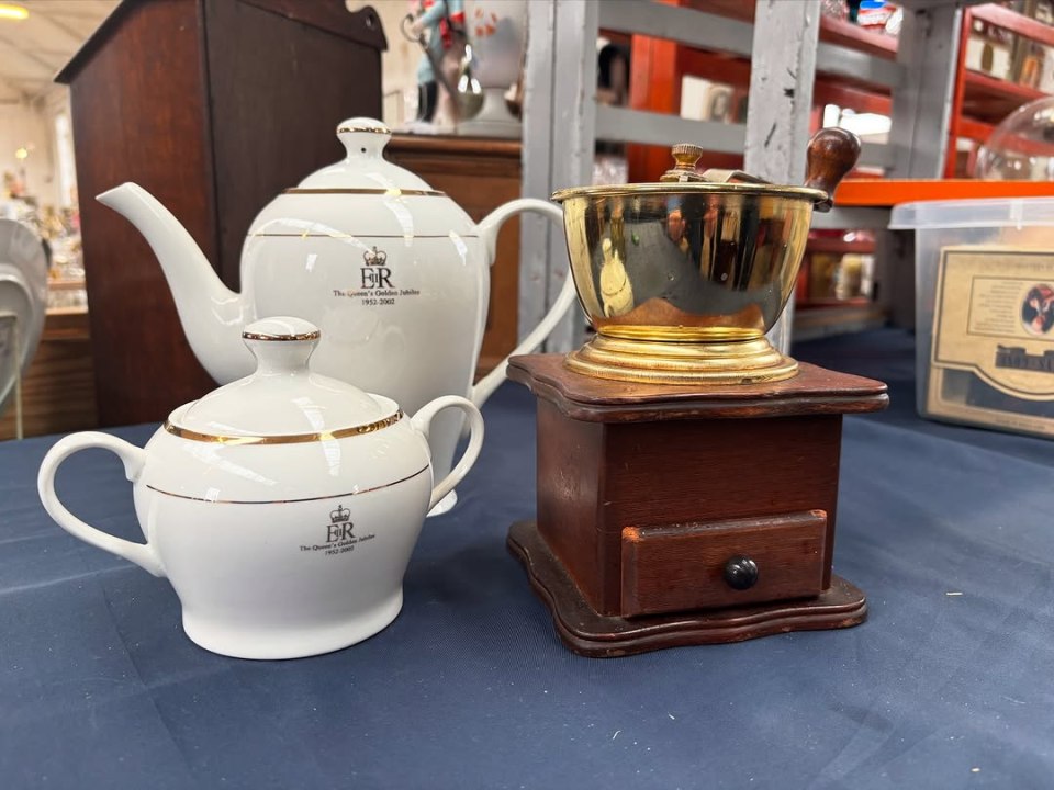 Teapot, sugar bowl, and coffee grinder on a table.