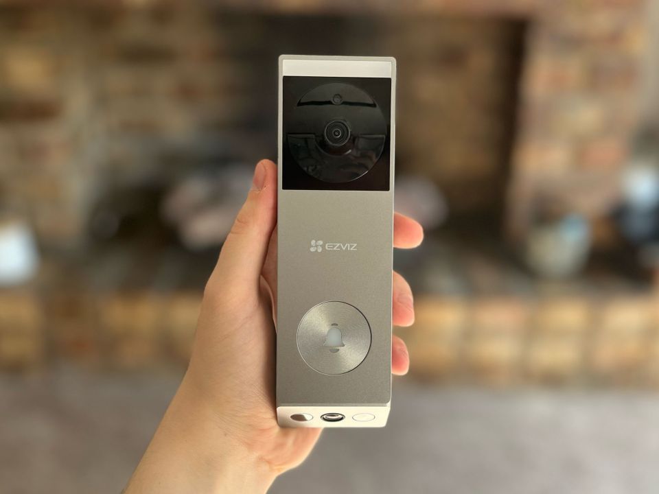 Hand holding EZVIZ video doorbell.