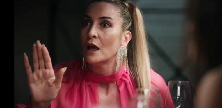 A woman in a pink shirt angrily confronts someone.
