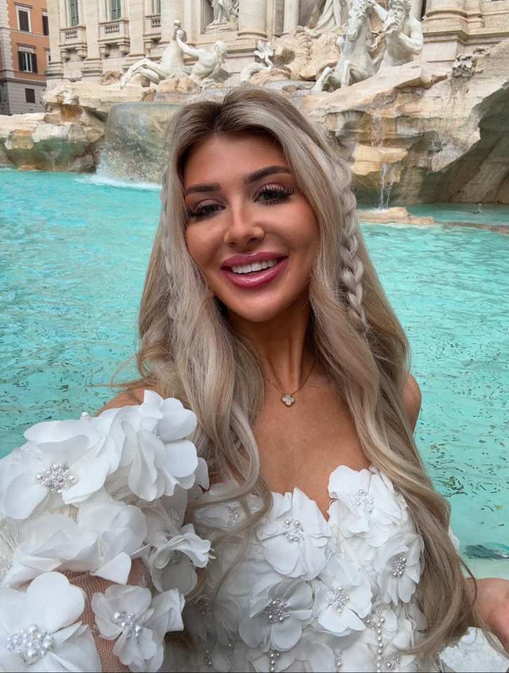 Woman in white floral dress at Trevi Fountain.