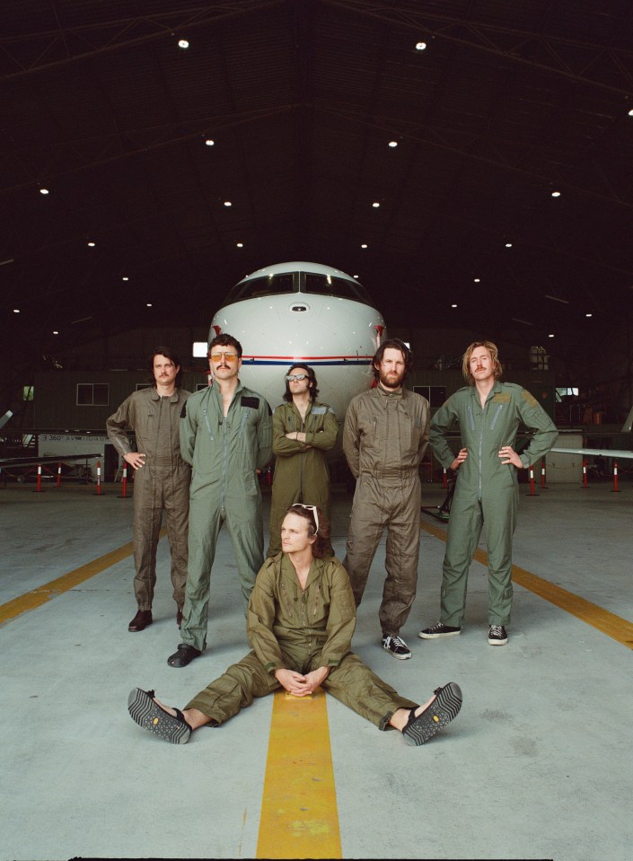 King Gizzard & the Lizard Wizard band photo in front of a plane.