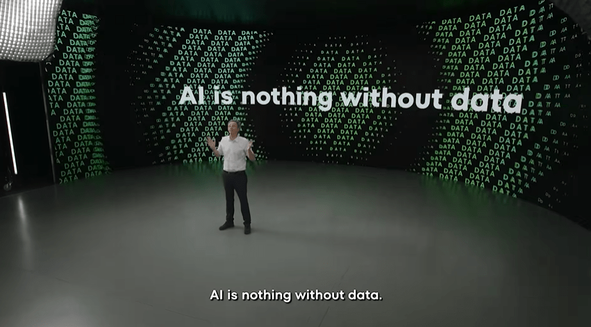 A man stands in a room surrounded by screens displaying the word "data," and text that reads "AI is nothing without data."
