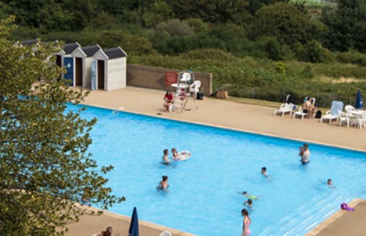 Outdoor pool with people swimming and sunbathing.