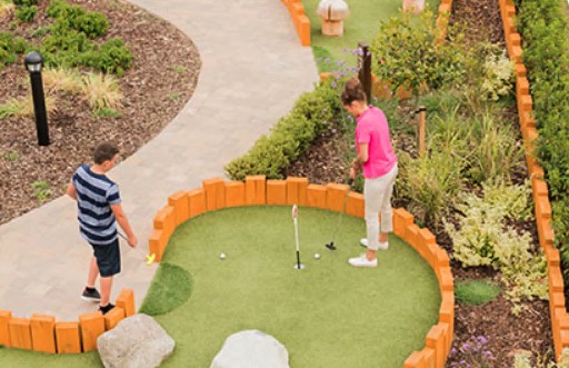Two people playing mini golf on a landscaped course.