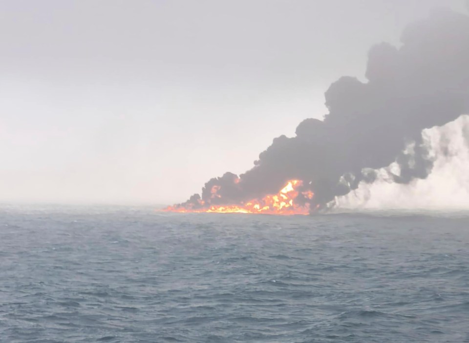 Burning ships and large smoke plume over the ocean.