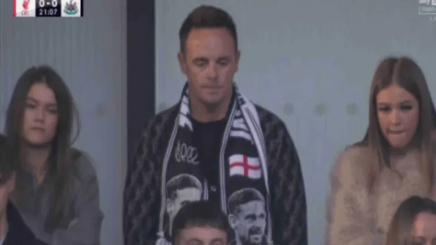 Man wearing a scarf with the England flag sitting between two women.