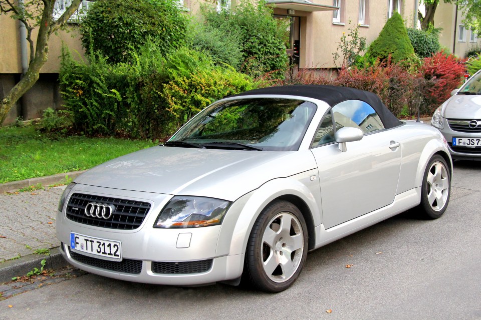 Silver Audi TT roadster parked on a city street.