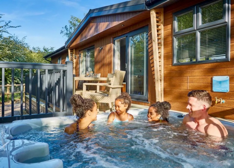 Family relaxing in a hot tub outside a cabin.