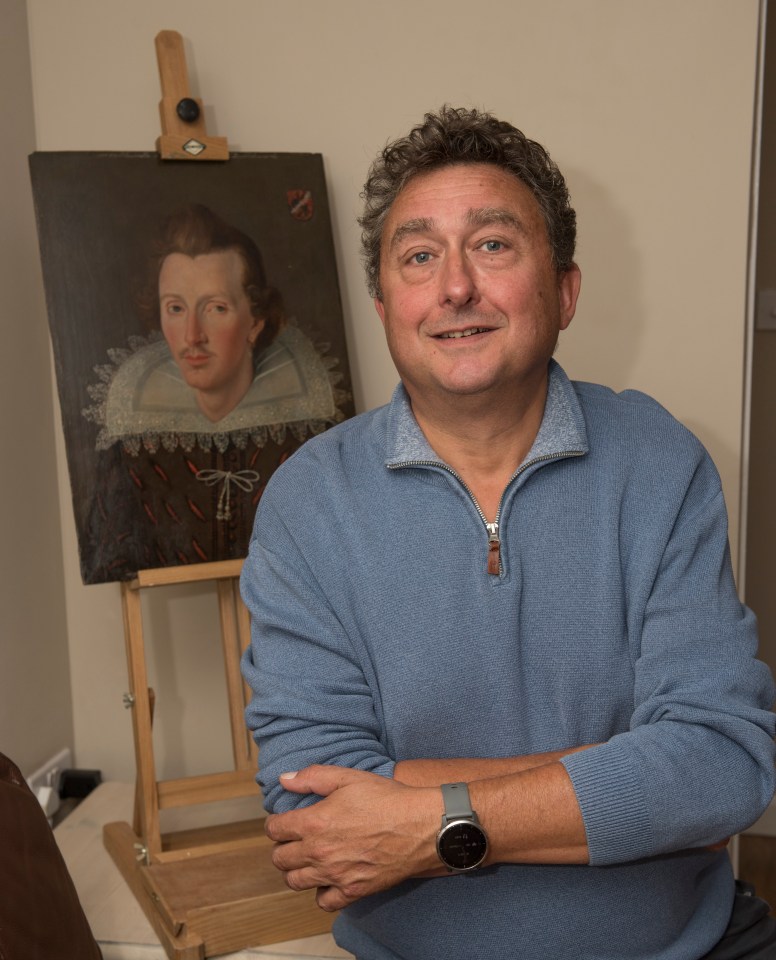 Man standing with arms crossed in front of a painting on an easel.