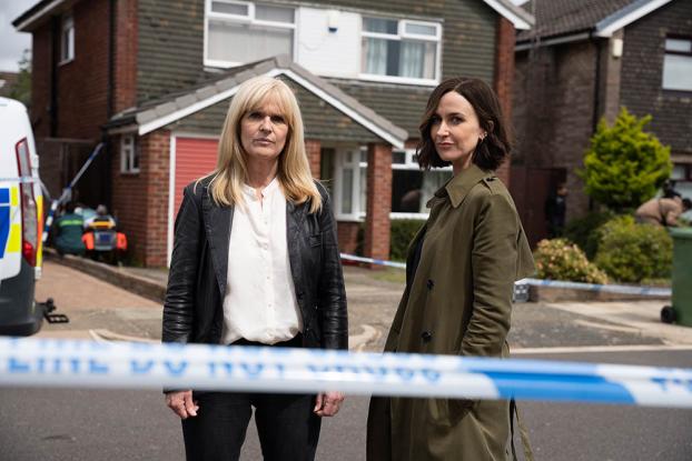 Two women standing in front of a house with police tape.