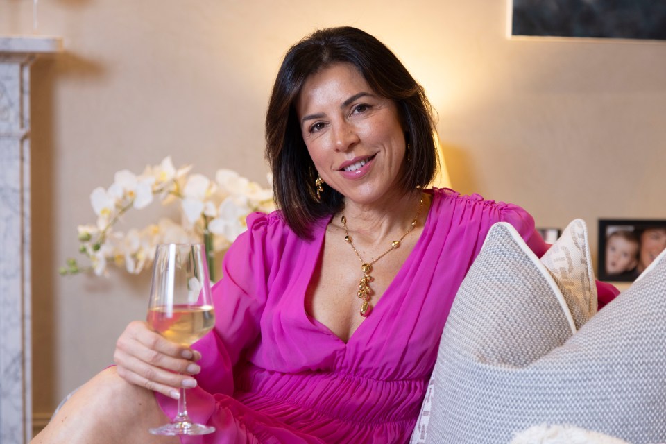 Woman in pink dress holding a glass of wine.