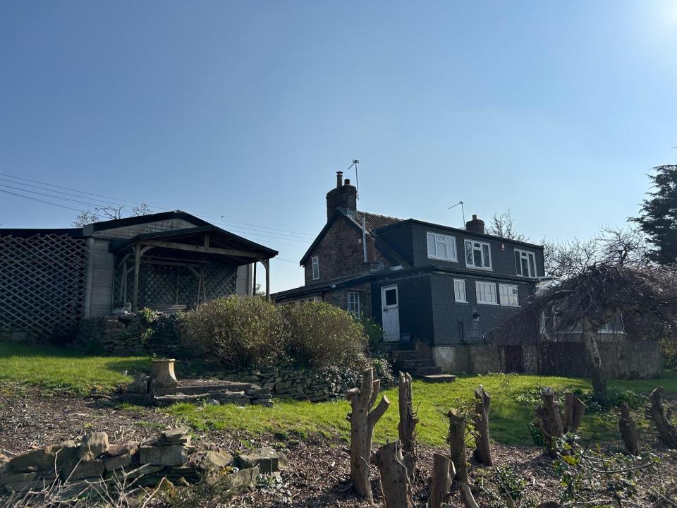 Cottage and outbuilding next to a larger house undergoing renovations.