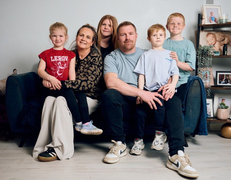 Family portrait of a mother, father, and four children sitting on a couch.