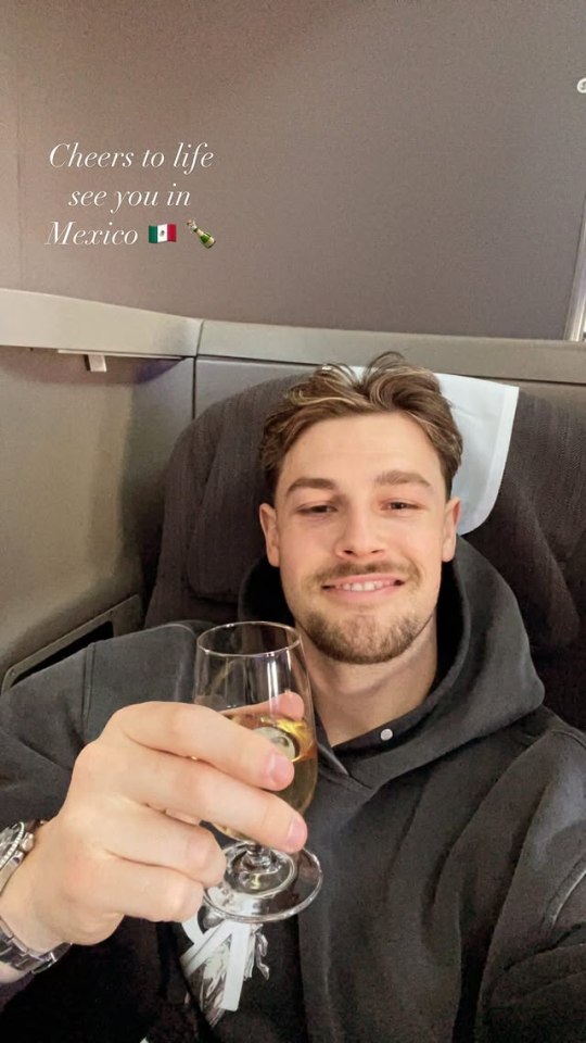 Andrew Le Page on a plane to Mexico, holding a glass of wine.