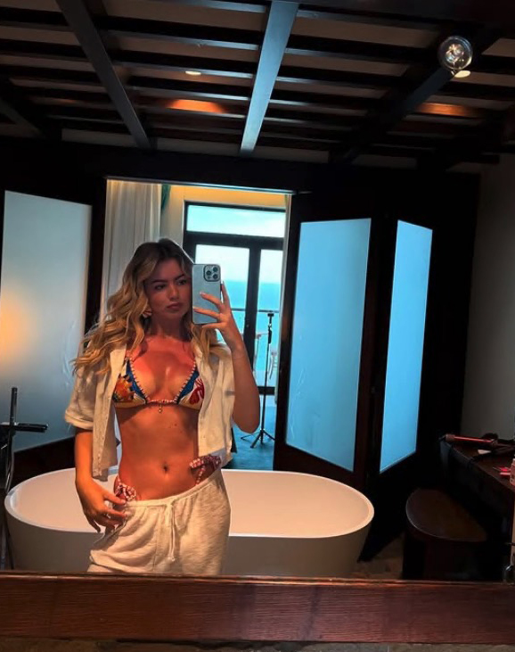 Tasha Ghouri in a bikini taking a selfie in a bathroom.