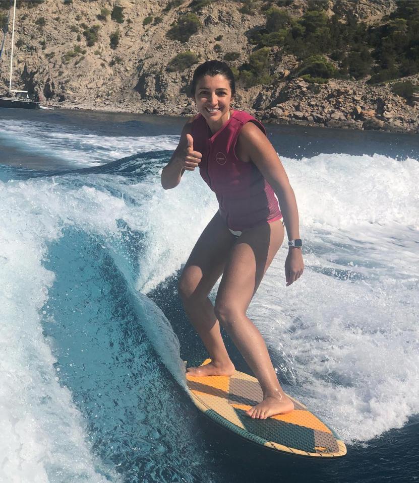 Woman wakeboarding and giving a thumbs up.