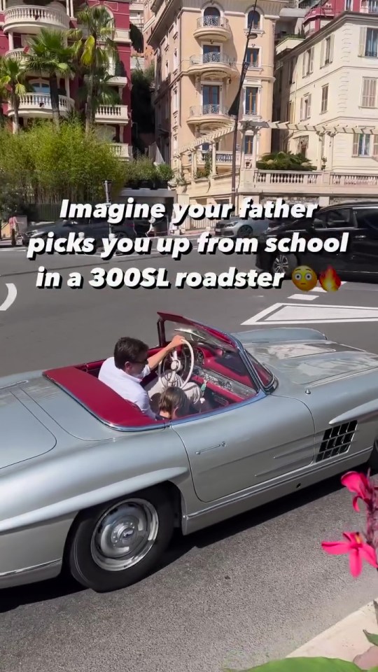 Man and child in a silver Mercedes-Benz 300SL Roadster.