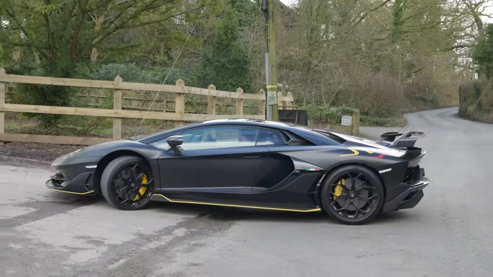 Black Lamborghini Aventador SVJ parked on a road.