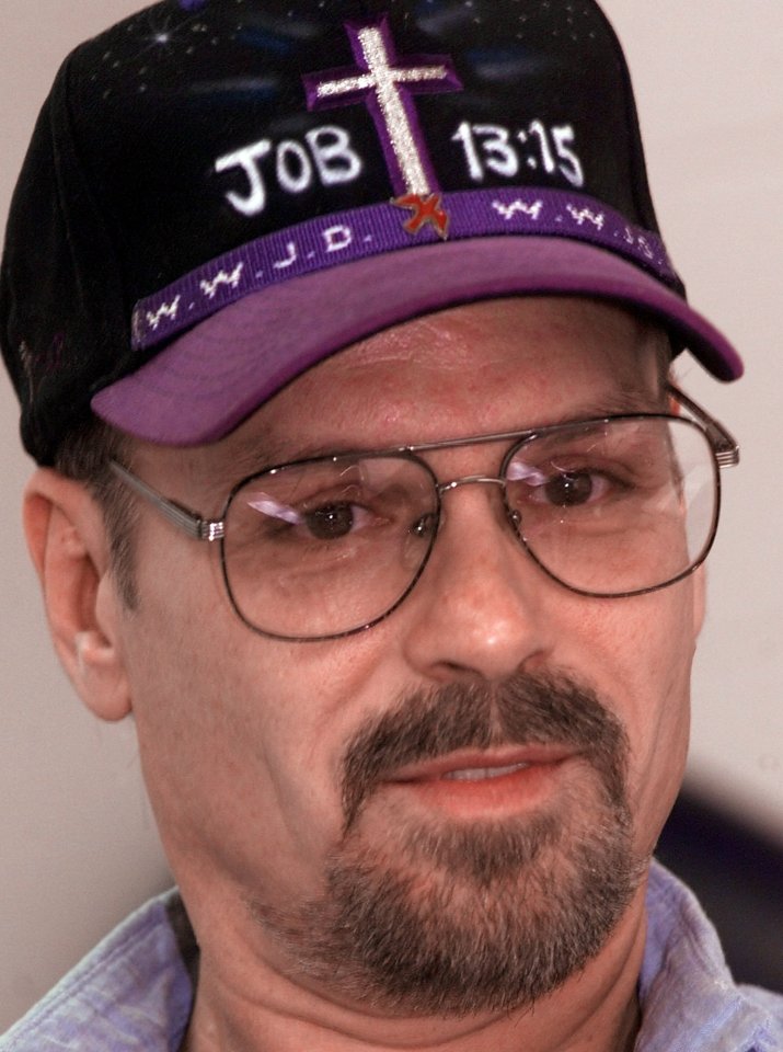 Close-up of Philip Workman, a convicted killer, wearing a baseball cap with a cross and Bible verse.