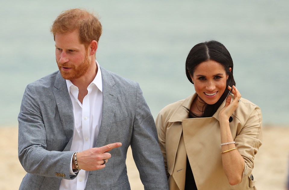 Prince Harry and Meghan Markle walking on a beach in Melbourne, Australia.