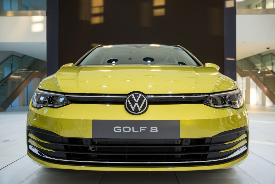 Yellow Volkswagen Golf 8 in a showroom.