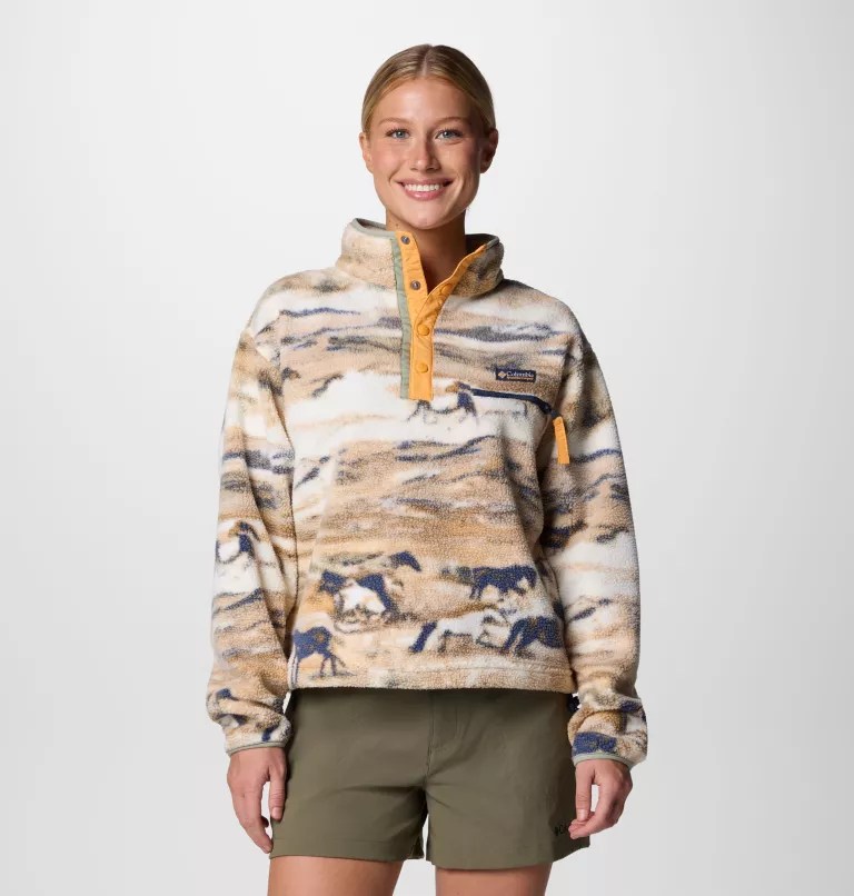Woman wearing a tan fleece pullover with a horse pattern.