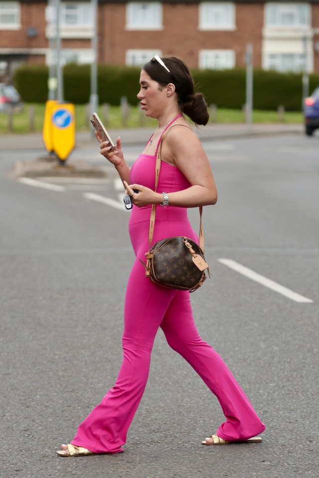 Chloe Brockett walking down the street, looking at her phone.