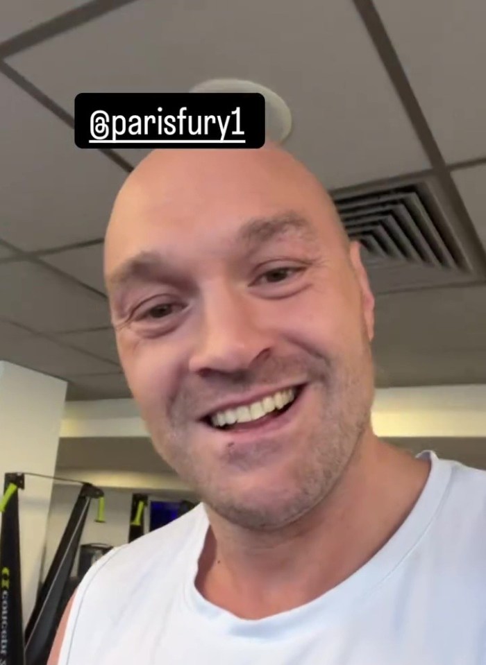 Tyson Fury in a gym, smiling at the camera.