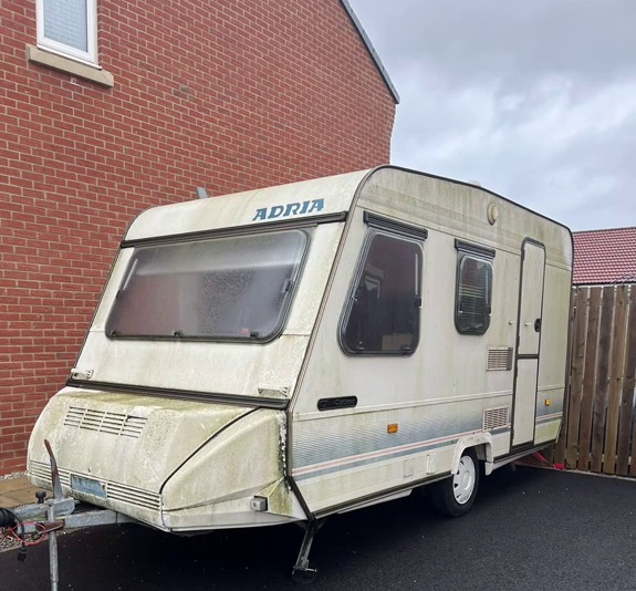 A weathered Adria caravan.