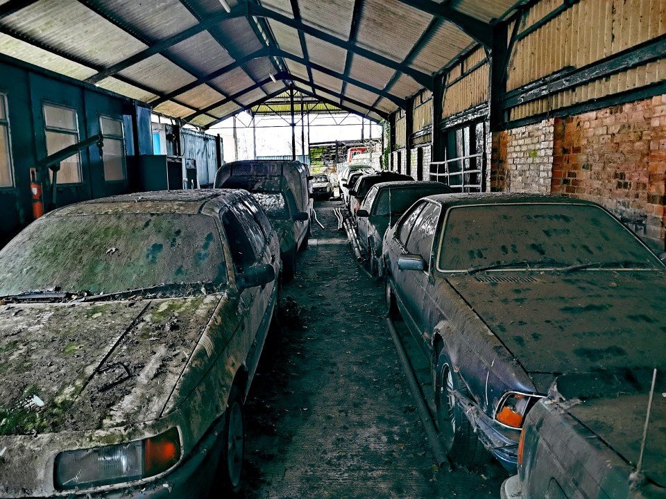 Neglected vintage cars and fire engines in a dilapidated garage.