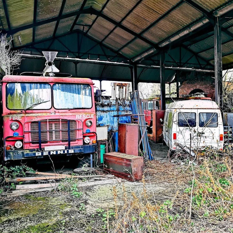 Abandoned fire trucks and other vehicles in a dilapidated barn.