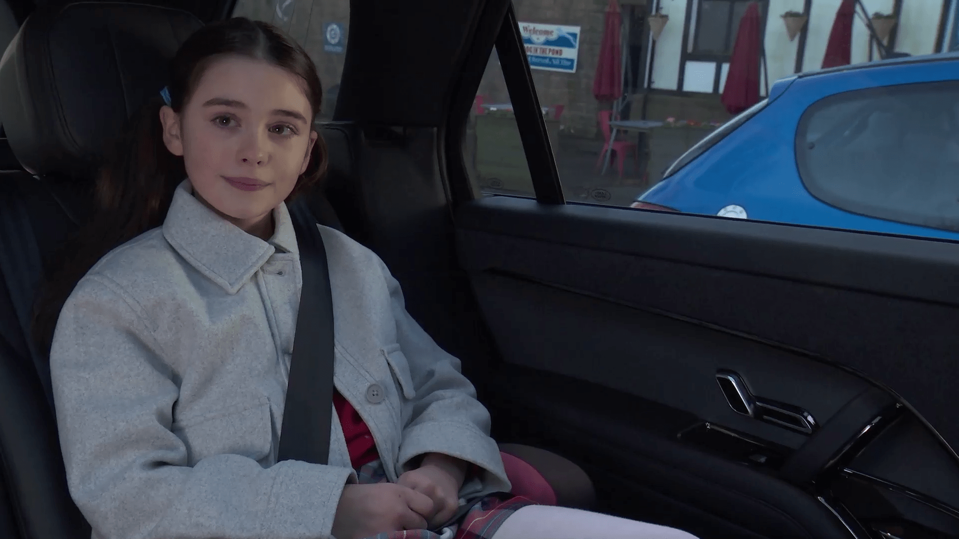 Girl sitting in the backseat of a car.
