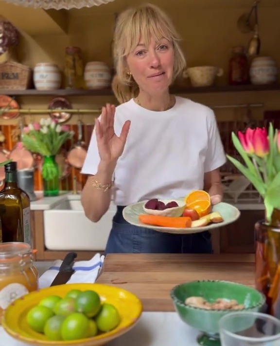 Woman holding a plate of fruit and vegetables.