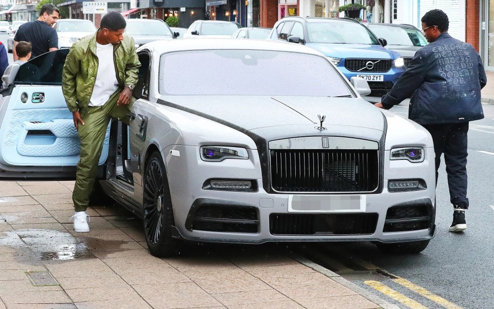 a silver rolls royce is parked on the side of the road