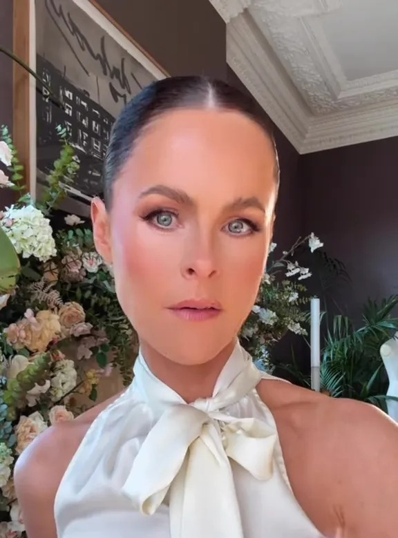 Woman demonstrating a hairspray hack to prevent makeup from staining white shirts.