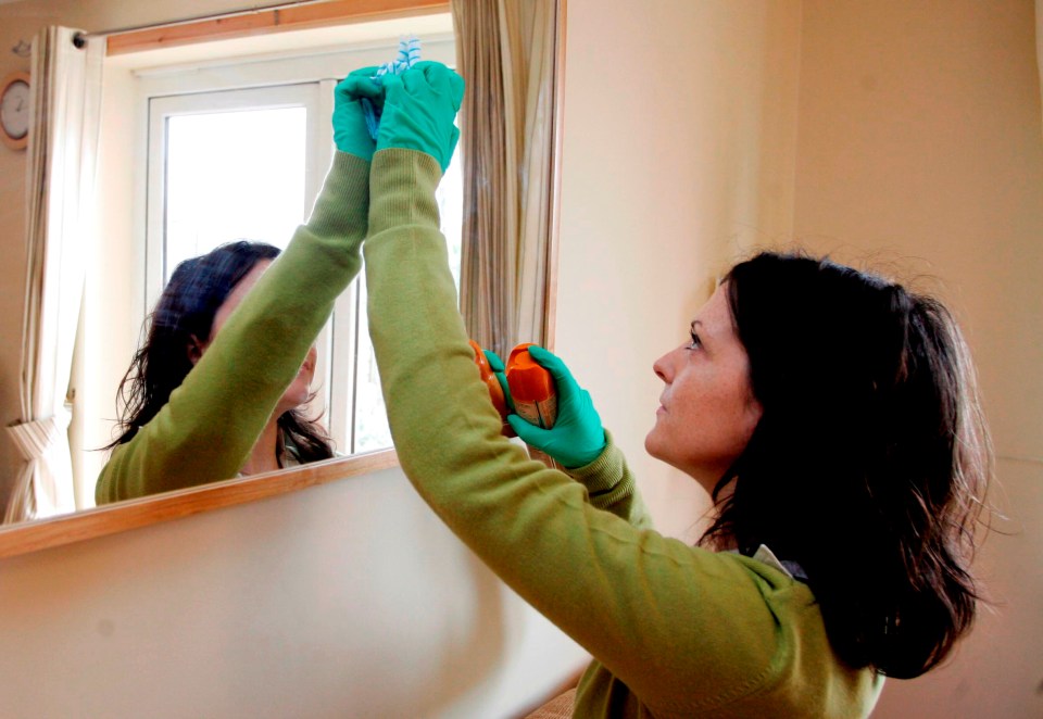 Woman cleaning a mirror.