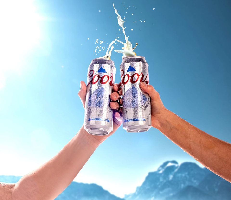 Two hands clinking Coors Light cans.