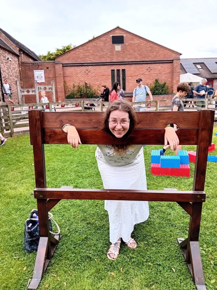 Woman playfully posing in a wooden pillory.