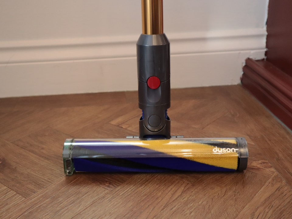 Dyson vacuum cleaner head on hardwood floor.