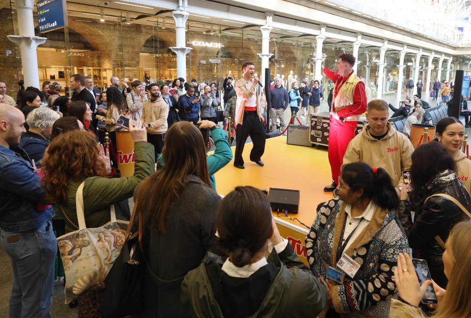 Two performers in 1980s-style outfits performing for a large crowd.
