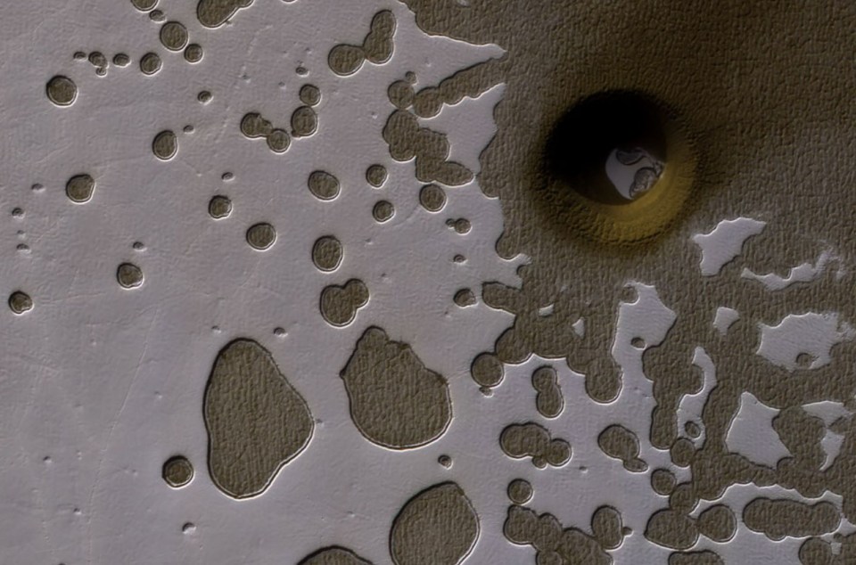 Mars surface with impact crater and smaller pits.