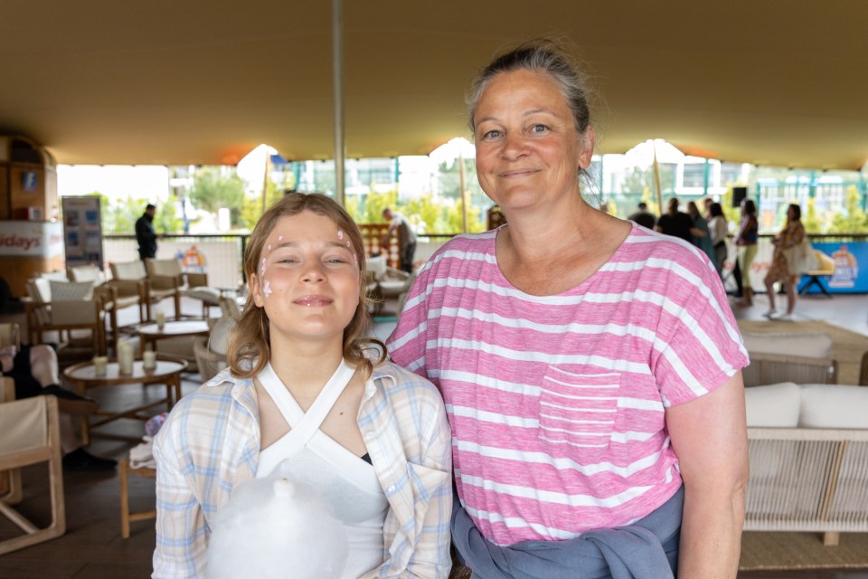 A girl with a sling and face paint smiles with her mother.