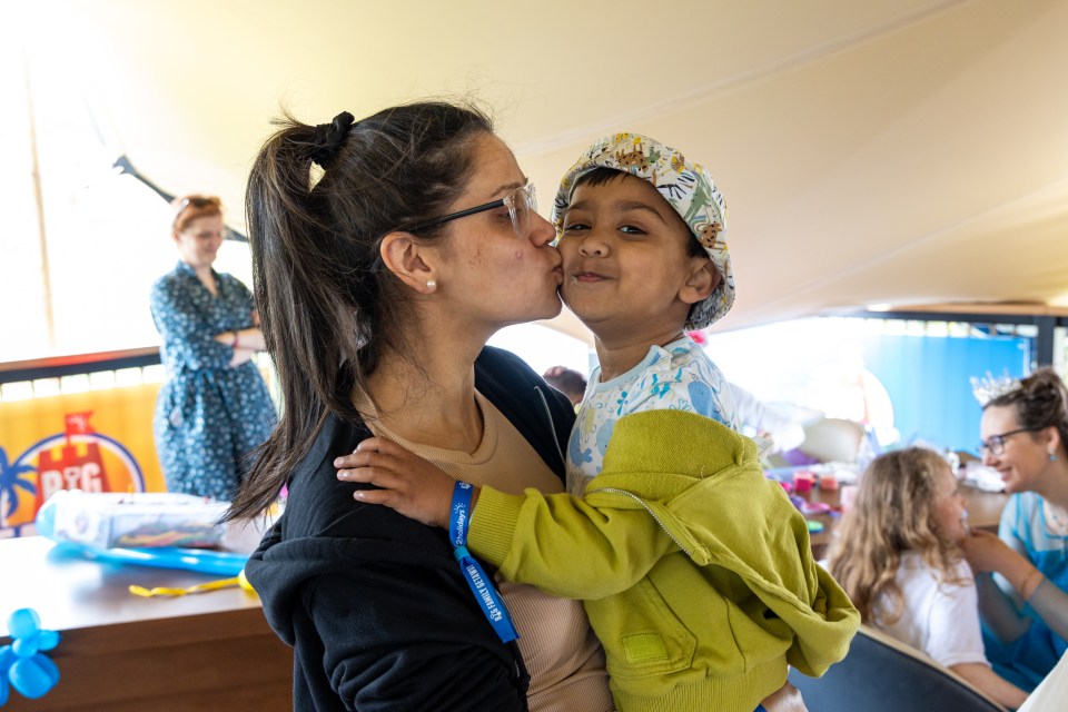 A woman kisses a young child on the cheek.
