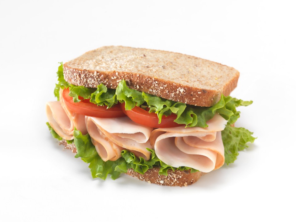 Smoked turkey sandwich on whole wheat bread with lettuce and tomato.