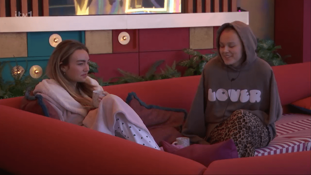 Two women sitting on a couch, talking.