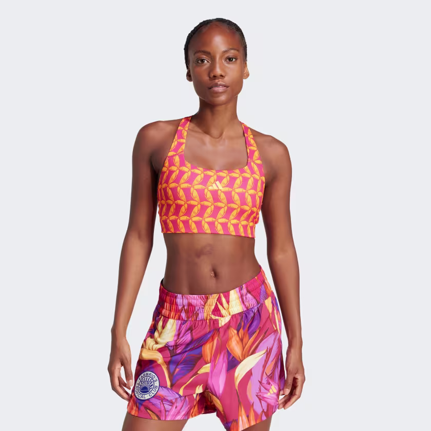 Model wearing an orange and pink patterned sports bra and floral print shorts.