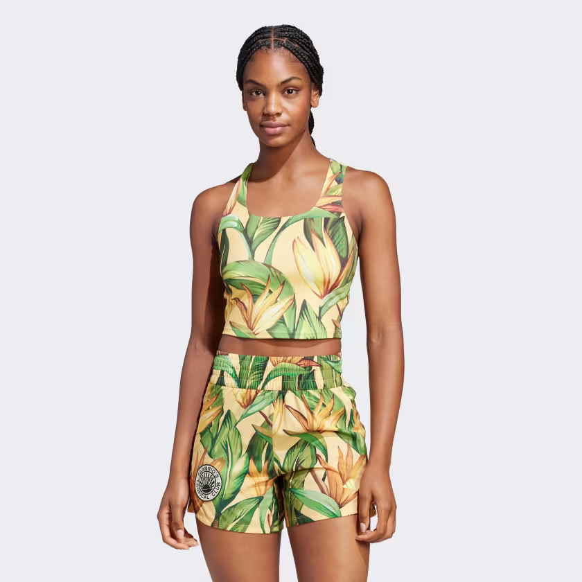 Model wearing a yellow tropical-print Adidas x FARM Rio training tank top and shorts.
