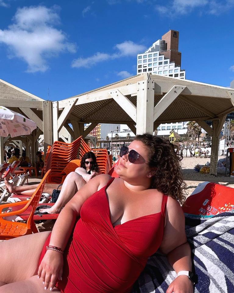 Woman in red swimsuit relaxing on a beach chair.
