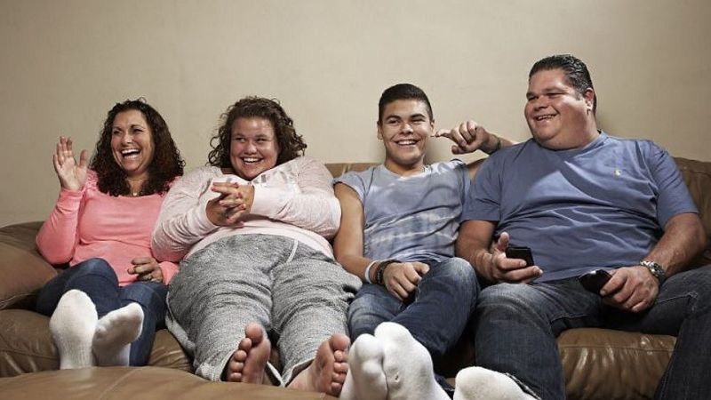 Family watching TV on a couch.
